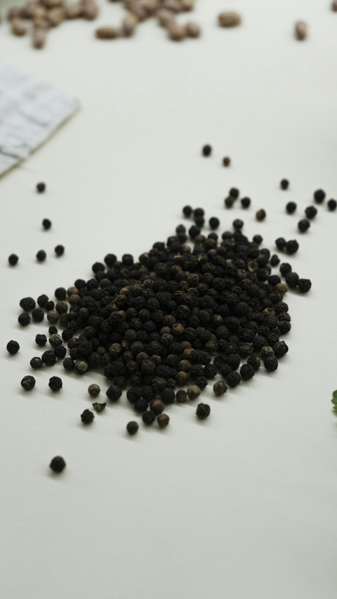 Black peppercorns on a light surface
