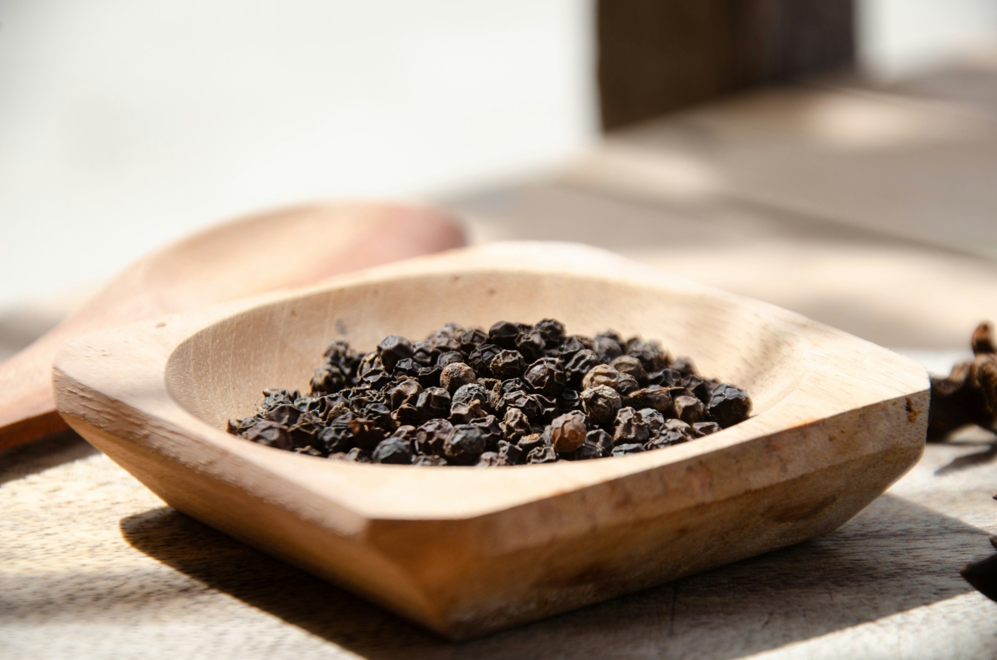 Black peppercorns in a wooden bowl